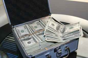 piles of u s dollar bills on silver and white suitcase